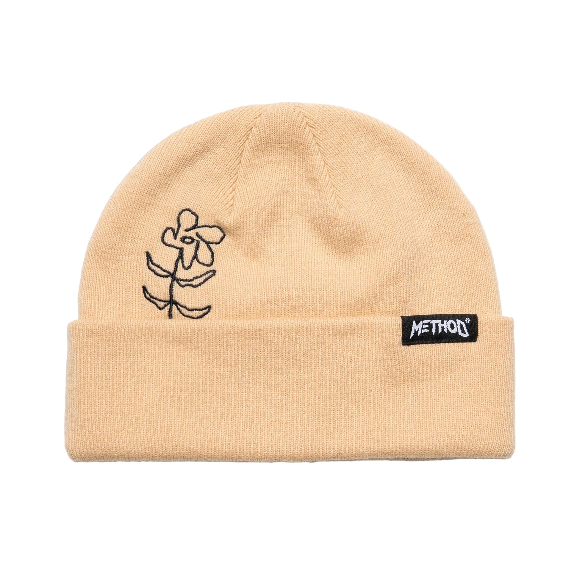 Beige beanie with black floral design and 'METHOD' logo on a light gray background