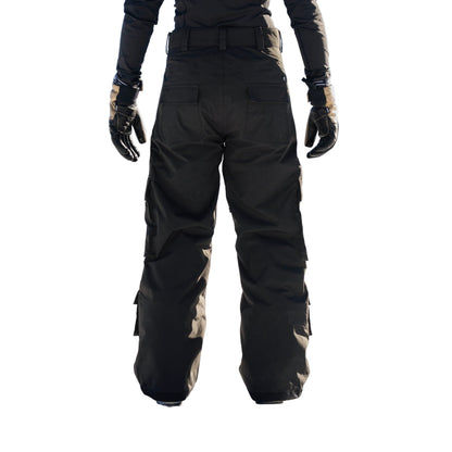 Person wearing black snow pants and gloves standing in a snowy landscape